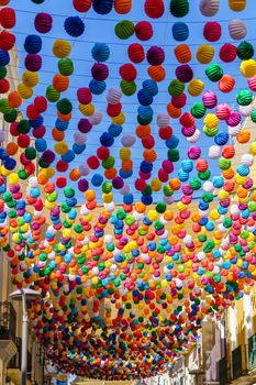 view of a street decorated with colored lanterns for the holidays, blue sky in the background