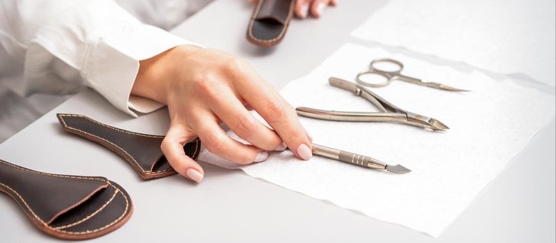 Manicure master lays out manicure set on a towel at the table in a nail salon