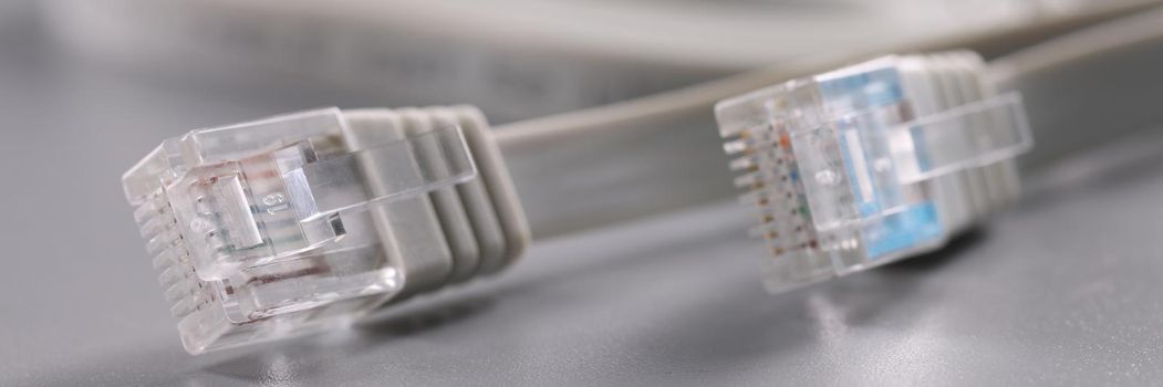 Close-up of pair of internet connectors on grey background, cable with plastic clip. Internet and telecommunications, modern technology, service concept