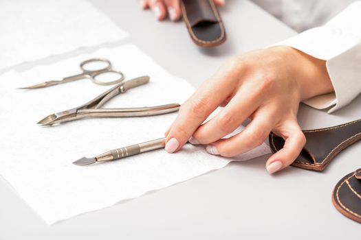 Manicure master lays out manicure set on a towel at the table in a nail salon