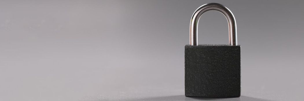 Close-up of solid metal locked padlock on grey background, thing to protect home or apartment. Protection equipment from break in. Safety, security concept