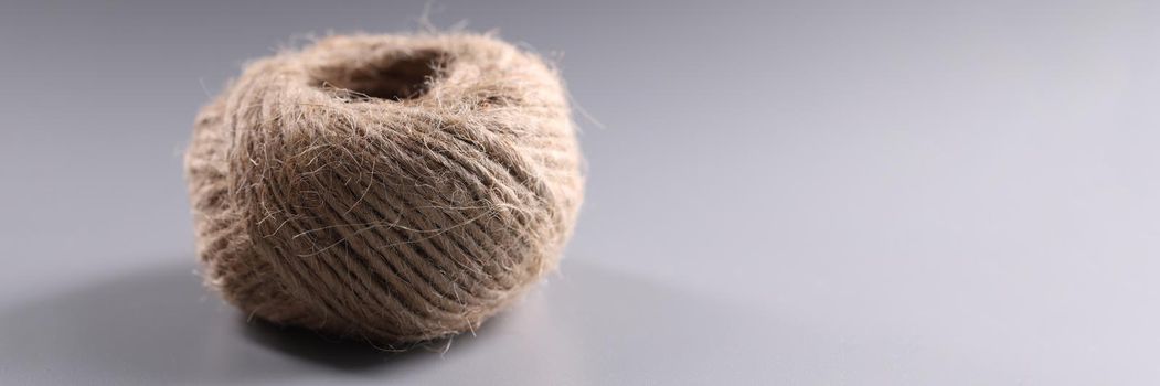 Close-up of brown rope roll, skein of jute twine on grey background. Ball of tangled thread. Hobby, equipment, knitting, needlework, handicraft concept
