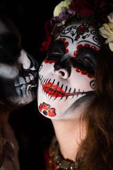 Man and woman in paired halloween costumes. Body art santa muerte and skeleton.