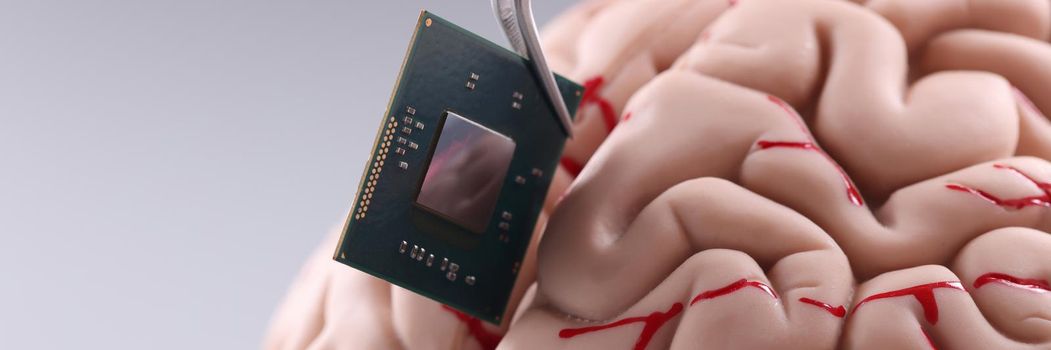 Close-up of someone put tiny computer chip detail in human brain with tweezer. Microprocessor in head. Future, modern technology, digital world concept