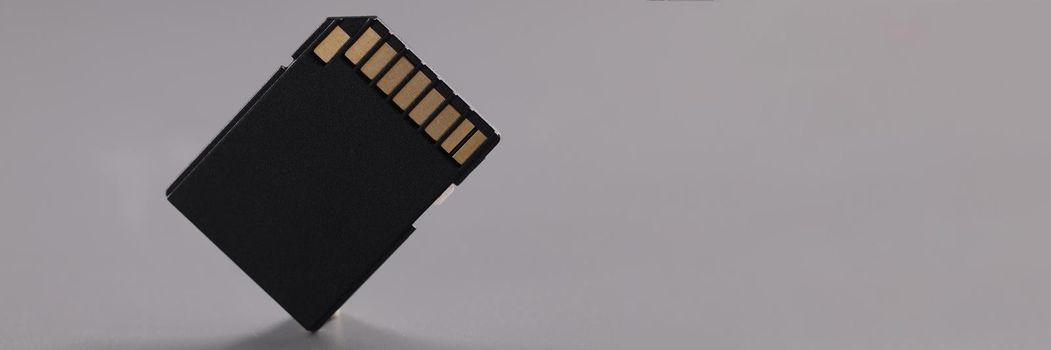 Close-up of black sd memory card, compact card with gold colored connectors. Detail for smartphone or laptop device. Modern technology, storage concept