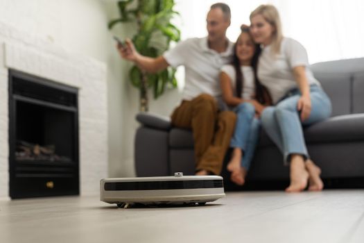 Smiling family pointing at robotic vacuum cleaner.