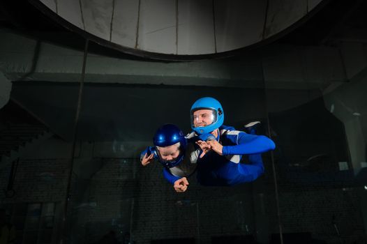 A man teaches a boy to fly in a wind tunnel. Lack of gravity