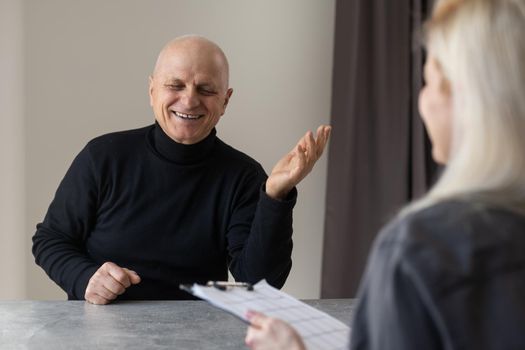 Portrait of female psychiatrist interviewing senior man during therapy session, copy space.