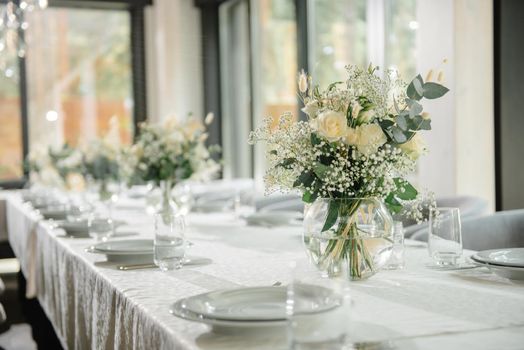 Wedding reception table in the restaurant decorated with white candles and flowers