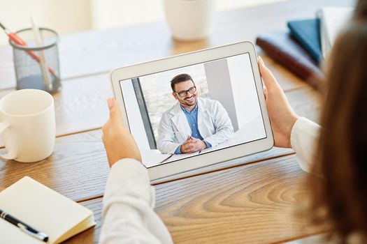 Back view of a woman making video call with her doctor while staying at home