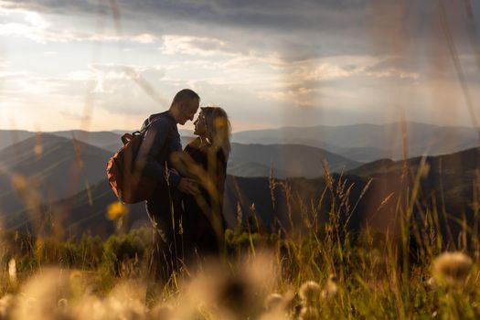 travel, tourism and people concept - happy couple with backpacks having fun over mountains background.