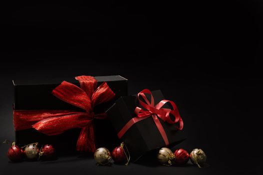 gift wrapped in dark black paper with luxury bow on dark background. Horizontal with copy space