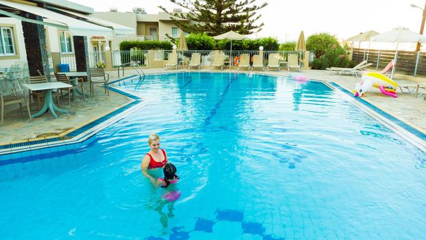 Beautiful woman with her daughter in swimming pool.