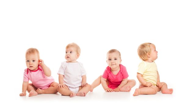 Group of witty babies sitting in different clothes, isolated on white background