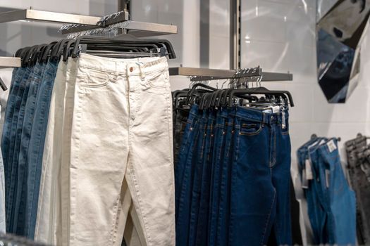 jeans hang on hangers on the counter in a fashion store. The concept of buying, selling, denim fashion. comfortable clothes