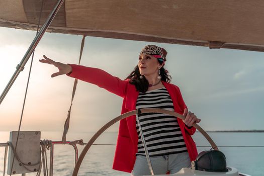Attractive middle-aged woman at the helm of a yacht on a summer day. Luxury summer adventure, outdoor activities