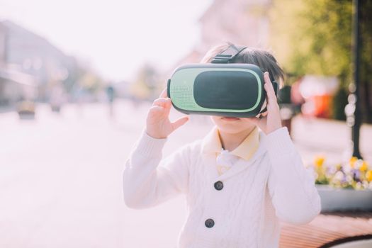 A boy is playing virtual reality glasses on the street . Modern gadgets. Children's games. The choice of virtual glasses. An article about virtual glasses. Modern children. Copy Space