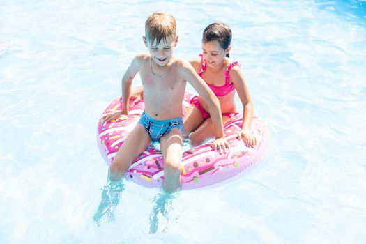 Kids having fun playing in swimming pool on summer vacation.