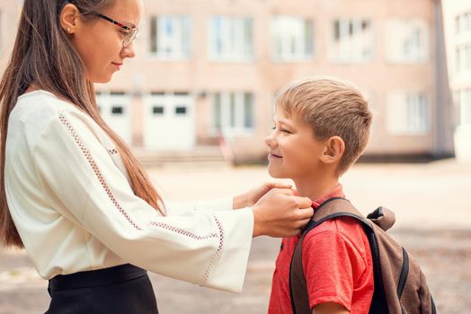 Elder sister helping her small brother in preparation for school, straightening the collar of the shirt