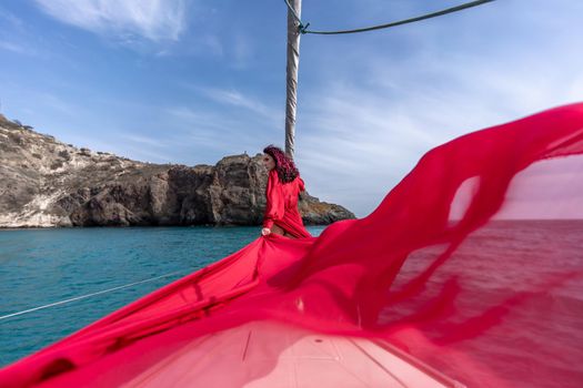 Attractive middle-aged woman in a red dress on a yacht on a summer day. Luxury summer adventure, outdoor activities