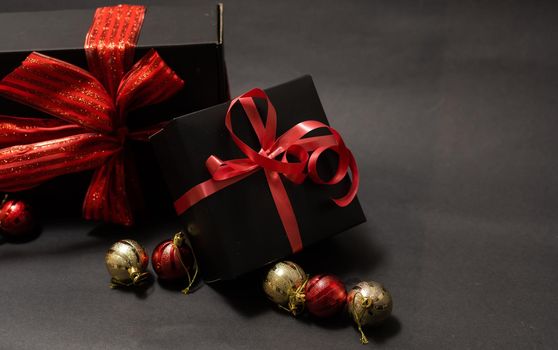 black gift box, balls, red Christmas decorations on the dark wooden background copy space.