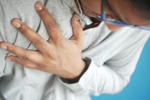 young man suffering pain in heart and holding chest with hand .