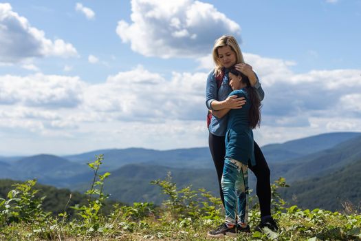 mother and daughter with backpack sitting on the footpath in the mountains at the day time.