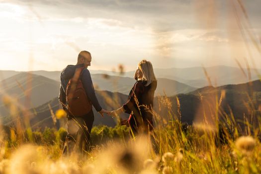 Man and woman standing and hugging on the top of the mountain, autumn hike with backpacks.