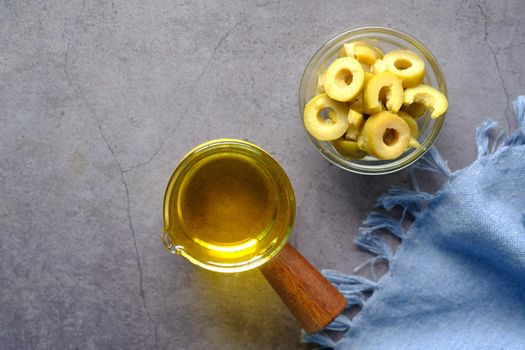 bottle of olive oil and fresh olive in a container on table