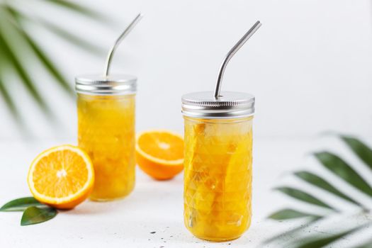 Glasses with orange juice, orange slices and mango on a gray background.