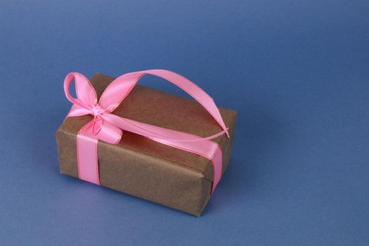 Brown gift paper box with pink bow and ribbon. A festive concert.