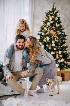 Happy family: mom, dad and pet. Family in a bright New Year's interior with a Christmas tree.