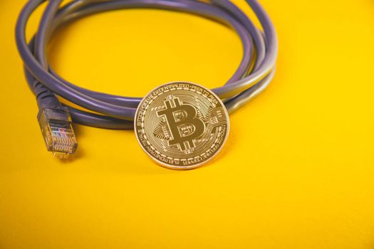 Internet payment for bitcoins. Internet cable and coin. Cryptocurrency as a means of payment. Bitcoin coin close up.