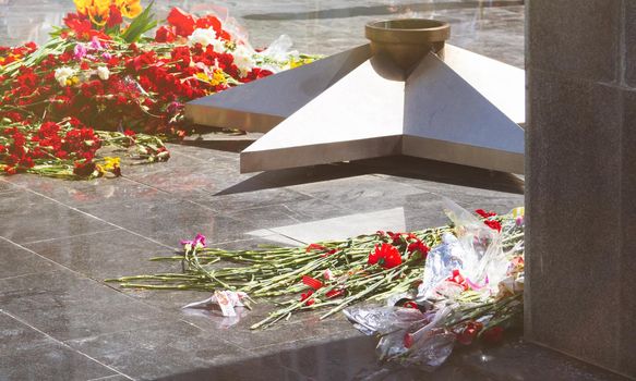 Commemorative memorial. Laying flowers at the eternal fire. Tribute to the memory of the fallen soldiers. Flowers and a soldering iron for soldiers.