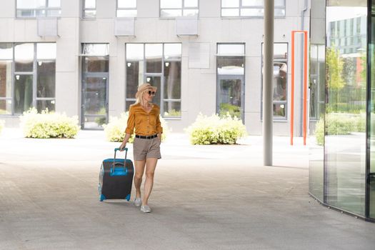Traveler suitcase, woman carrying a suitcase in a travel location on holidays trip with lens flare technique, traveling on holidays concepts.