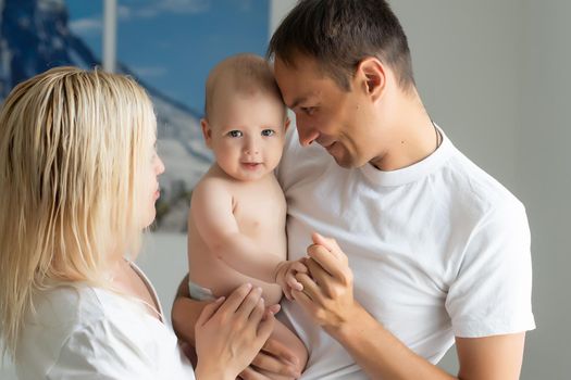 A Happy young family with baby in white bedroom.