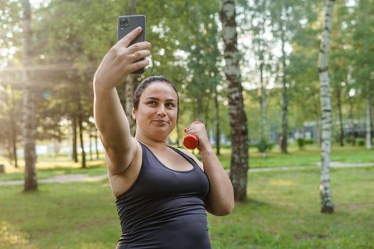 A charming brunette woman plus-size body positive practices sports in nature.