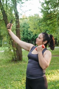 A charming brunette woman plus-size body positive practices sports in nature.