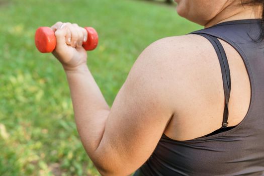 A charming brunette woman plus-size body positive practices sports in nature.