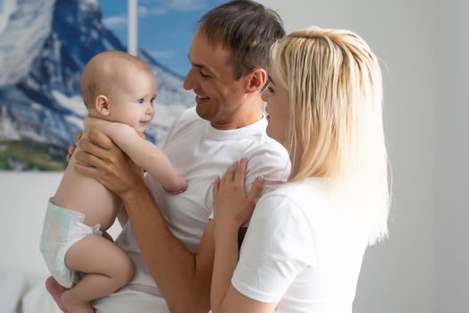 A Happy young family with baby in white bedroom.