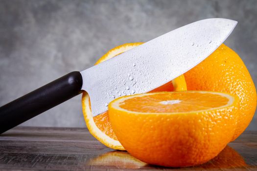 Slicing oranges side view. A man cuts an orange with a knife. The process of making juice from fruits. Knife and orange.