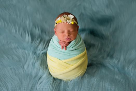 Ukrainian newborn child in the studio patriotic blue yellow colors during the war in Ukraine 2022. A little baby, girl sleeps in cocoon