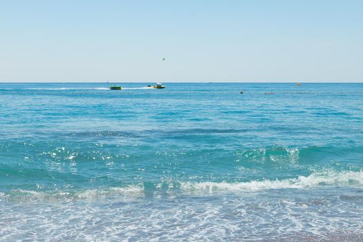 Soft wave of the turquoise sea on the sandy beach. Natural summer background with copy space