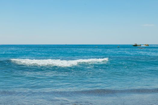 Soft wave of the turquoise sea on the sandy beach. Natural summer background with copy space