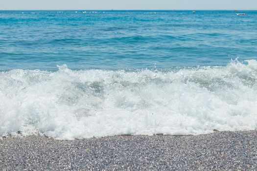 Pebble beach with azure sea water texture background
