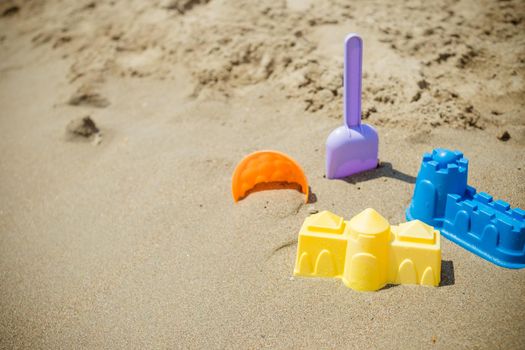 Bright plastic children's toys in the sand. Concept of beach recreation for children. Children's summer games. Summer concept. Flat lay, top view, copy space