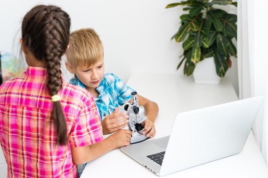 renewable energy, children, technology, science and people concept - kids or friends with laptop computer and microscope model.