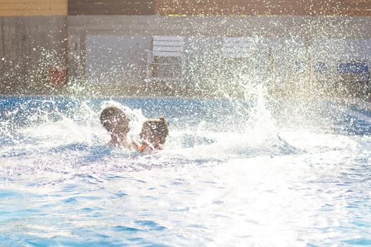 father catches little girl jumping in pool against sea.