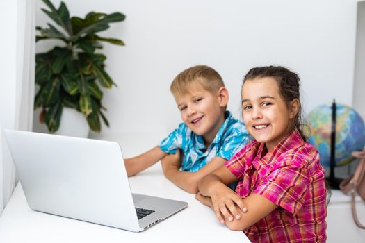 Cute children use laptop for education, online study, home studying, Boy and Girl have homework at distance learning. Lifestyle concept for home schooling