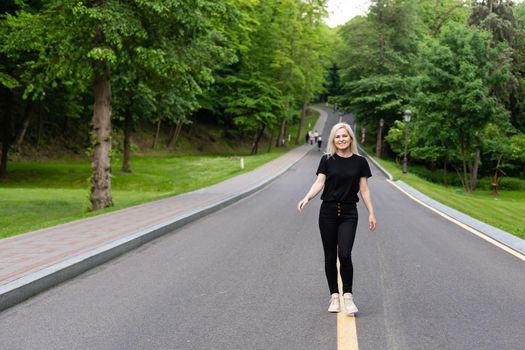 Attractive young woman walks along the line of the road enjoying nature